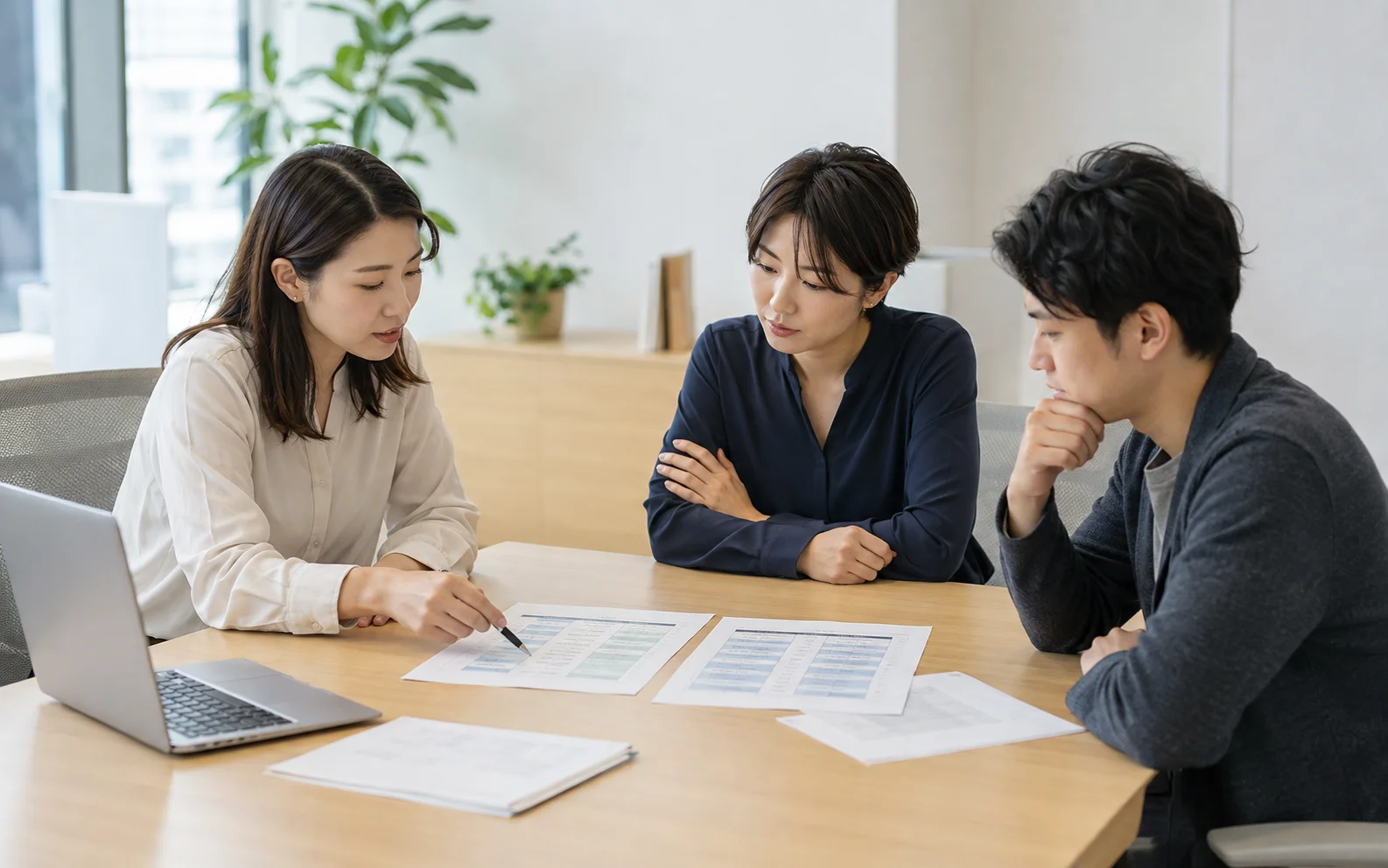 担当者が研修計画の資料を見比べながら話し合うイメージ
